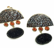 These unusual earrings were made by Dyanne Belle with stones purchased from our Gemstone Roundtable. The Dinosaur bones and black drusys are set in rhodium plated silver and the orange sapphires in 14k gold.